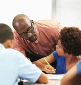 Academic Approach Tutoring and Test Prep | A teacher helping a group of students in a classroom.