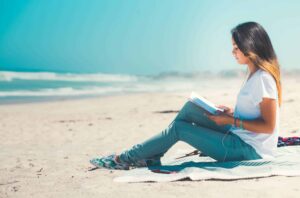 Academic Approach Tutoring and Test Prep | A woman sitting on the beach reading a book.