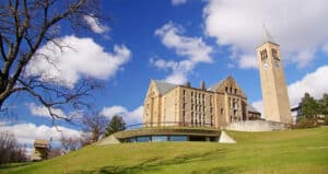 Academic Approach Tutoring and Test Prep | View of a university campus with a historic stone building, a modern glass structure, and a tall clock tower under a blue sky with scattered clouds.