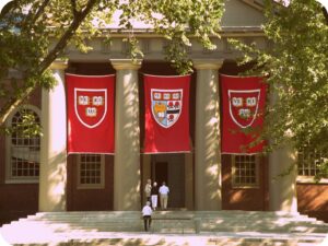 Academic Approach Tutoring and Test Prep | A traditional building with three large red banners displaying shields and class years, hung on its facade, with people on the entrance steps.
