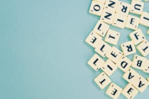 Academic Approach Tutoring and Test Prep | Scattered Scrabble tiles with random letters on a light blue background, mostly clustered in the upper right corner with empty space on the left.